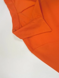 Close-up of bright orange breathable mesh fabric with collar and seam detail