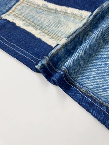 Detail shot of denim print fabric featuring blue and white patchwork with double stitching
