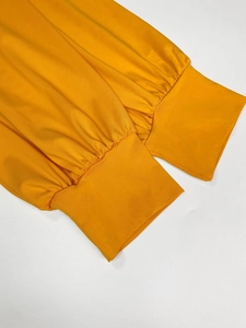 Detailed close-up of elastic ribbed cuffs on a bright orange V-neck long maxi dress