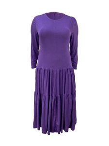 Detail of a dark purple pleated tiered dress with a classic round neck and long sleeves