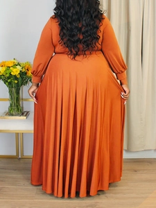 Detail of rust red maxi dress showing elegant flowing pleats and high waist design