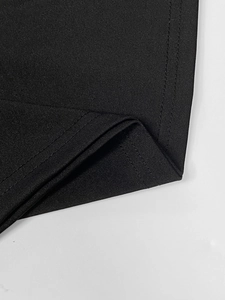 Detailed macro view of black knitted dress hemline with high-density double stitching