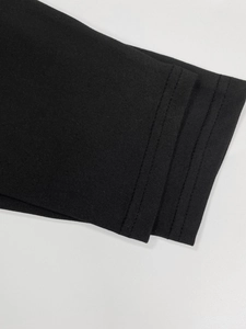Detailed close-up showing the double-needle stitching on the black knitted dress sleeve