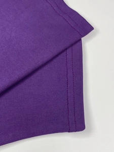 Close-up of pleated purple fabric dress with durable double-needle stitching on the hem