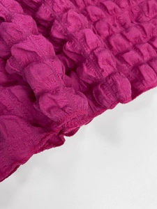 Gros plan sur le tissu gaufré rose foncé avec des détails de couture précis