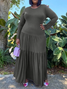 Plus size dark grey tiered dress with long sleeves and round neck in outdoor setting