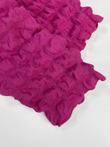Détail de la texture du tissu popcorn rose rouge avec design plissé à bulles élastiques
