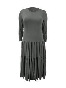 Close-up of pleated tiered dress hem with long sleeves in dark gray soft fabric
