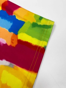 Macro detail showing double-stitched hem and vibrant colorful tie-dye print on soft knit fabric