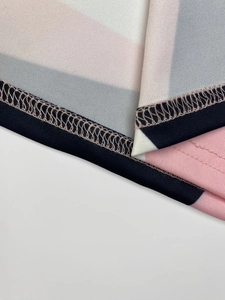 Detail view of the geometric print dress fabric showing precise overlock stitching and texture