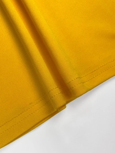 Detail view of bright yellow knitted fabric with high-quality double-needle stitching