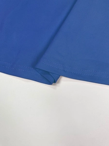 Detailed close-up of high-quality double-stitch hem on blue V-neck dress fabric
