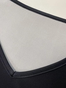 Détail de l'élégant col en V sur une robe en maille contrastée noire et grise