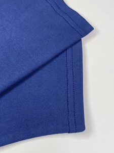 Detail of high-density knit fabric and double-needle stitching on dark blue pleated dress