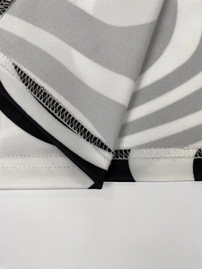 Detail of the hem featuring double-needle stitching on the black and white spiral dress