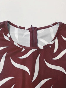 Detail showing the burgundy round neckline with white leaf print and invisible back zipper