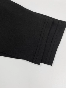 Detailed close-up showing professional double-needle stitching on black knit dress fabric