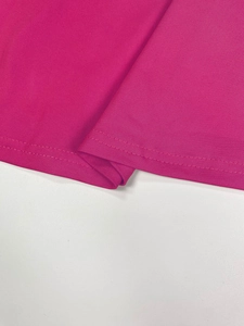 Macro detail of high-quality stitching on the hem of a vibrant rose red V-neck dress