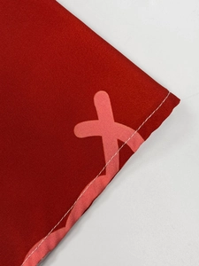 Macro view of red fabric texture with pink cross print and white stitched edge detail