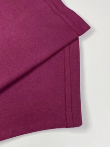 Close-up of double-needle flat-sewn stitching on burgundy pleated dress fabric