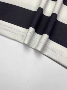 Detailed macro view showing high-quality double-stitch hem on black and white striped dress
