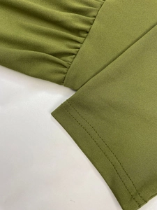 Detail view of olive green knit fabric with elegant pleated texture and flatlock stitching