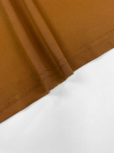 Close-up of brown knit fabric showing precision double-needle stitching and fine texture