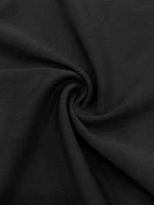 Gros plan sur la texture du tricot noir avec un pli en spirale montrant le détail du tissu
