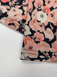 Détail du tricot floral montrant la couture précise à double aiguille sur l'ourlet