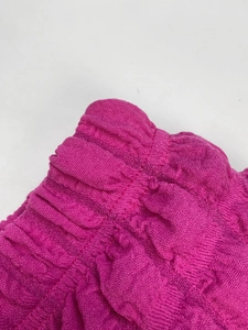 Macro detail of high-elasticity pleated waist and textured bubble fabric in rose red color