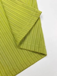 Detail shot of bright green ribbed knit fabric hem with precise double-needle stitching