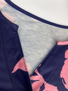Detail of V-neckline with abstract pink floral print on dark blue fabric