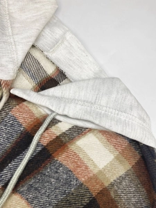 Close-up of a plaid hooded jacket with navy and orange check pattern and grey drawstrings