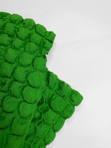 Macro shot of bright green bubble textured fabric with fine stitching for women dress