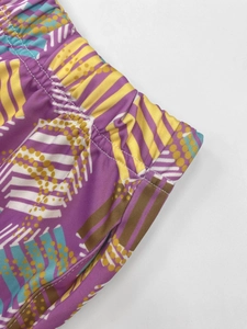 Detailed view of elastic waistband on purple joggers with colorful geometric patterns
