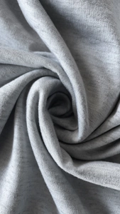 Close-up of light grey melange knit fabric showing soft texture and premium weave