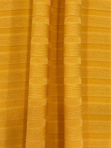 Detail of mustard yellow knit fabric showing ribbed texture and elastic material properties