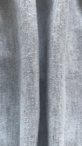 Close-up of soft grey heather knit fabric texture with uniform vertical drape folds