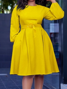 Detail of elegant yellow long-sleeved dress with waist belt and pleated skirt design