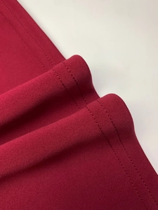 Detailed macro view of double-stitched hem on a dark red elegant knit dress fabric