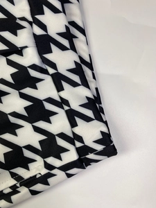 Détail du pantalon large à motif pied-de-poule montrant la texture et les coutures du bas