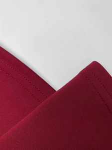Close-up of burgundy knit fabric showing high-quality double-needle stitching and texture