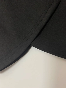Detail of black twill fabric showing professional double-needle stitching on the hemline