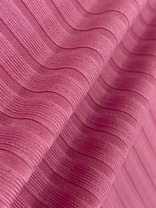 Detailed macro view of vibrant rose pink ribbed knit fabric with soft texture