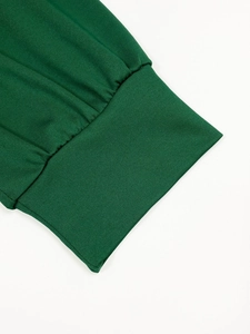 Detailed close-up of dark green ribbed knit cuff with elegant pleated stitching design