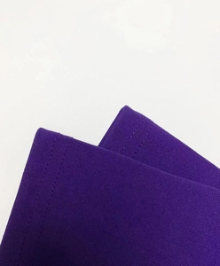 Détail de la manche d'une robe en tricot violet foncé montrant une couture double aiguille
