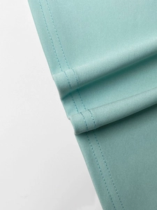 Detail shot of mint green knit fabric showing premium double-needle stitching and texture