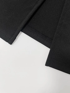 Detailed close-up showing slit design and neat overlock stitching on black fabric dress