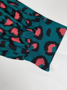 Dettaglio della stampa leopardata verde e rosa con eleganti polsini ampi a pieghe