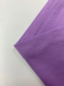 Nahaufnahme eines violetten Kleides mit robuster Doppelnaht und feiner Stoffstruktur
